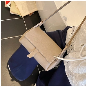 Close-up of oatmeal leather pillow bag featuring white contrast stitching and grainy texture