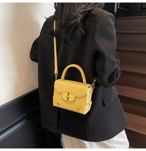 Detail of yellow pebbled leather handbag with gold metal twist lock and stud decor