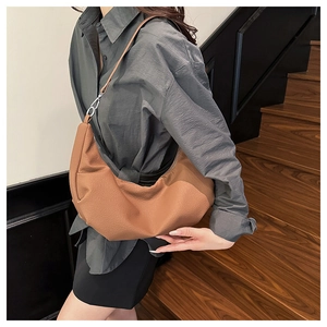 Brown soft leather hobo bag with sleek metal zipper and adjustable shoulder strap on model