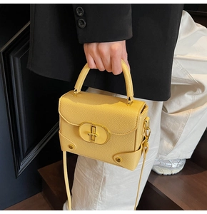 Detail of yellow lychee pattern handbag featuring gold twist lock and metal rivet accents