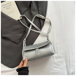 Detailed view of silver pebble leather texture and adjustable strap on a flap bag