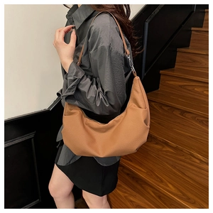 Brown leather crescent tote bag with pebble grain texture and stylish side pleats