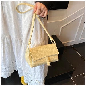 Détail d'un sac à bandoulière gaufré jaune clair avec rabat et fine bandoulière élégante