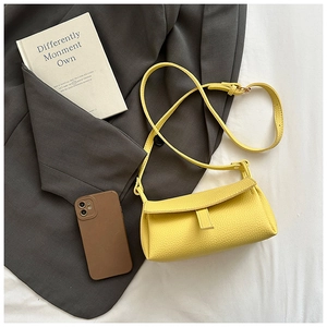 Detailed flat lay of a yellow leather flap bag with fine stitching and adjustable strap