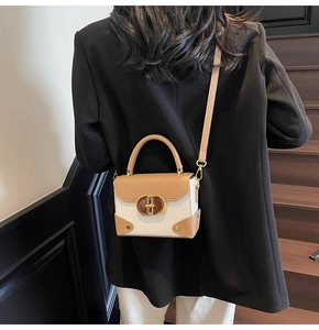 Detail of color-block mini bag with gold oval lock on a leather strap over a blazer