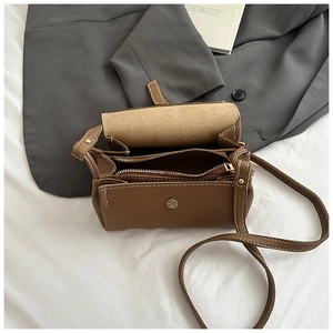 Detail of brown pebbled leather crossbody bag showing interior pockets and white stitching