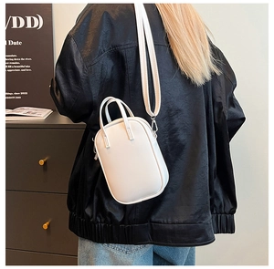 Back view of model wearing a minimalist white leather crossbody bag with detachable strap