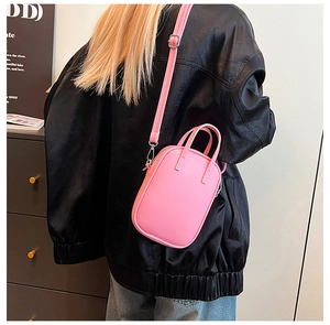 Bright pink mini crossbody bag worn over a black leather jacket for a stylish look