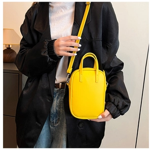 Model wearing a bright yellow rectangular crossbody bag with dual handles and strap