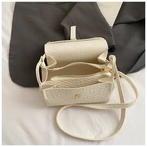 Détail du sac bandoulière blanc à motif croco montrant les compartiments et ferrures dorées