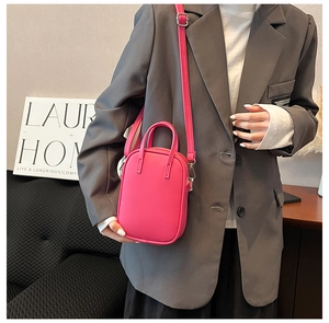 Close-up of bright pink leather crossbody bag paired with charcoal grey blazer jacket