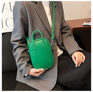 Detail of vibrant green mini crossbody bag styled with a gray blazer for a modern commute
