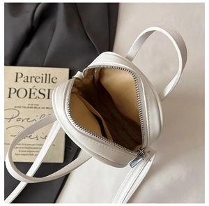 Interior view of white round crossbody bag showing fabric lining and small side pocket