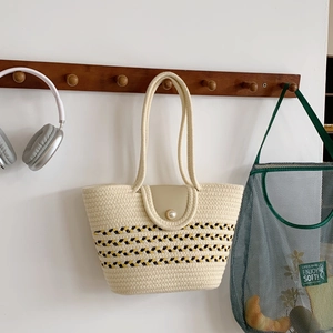 Retro-Strohhandtasche mit Perlenschnalle und Streifenmuster in natürlichem Ambiente