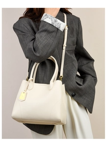Close-up of cream textured leather tote bag showing golden hardware and handle details