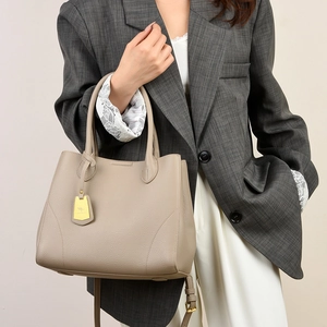 Close-up of pebble grain leather tote bag with gold kangaroo logo charm and strap