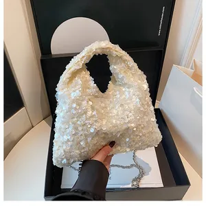 Detail of white sequin handbag with metallic chain displayed in a gift box