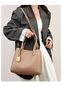 Close-up of brown litchi pattern leather handbag with gold hardware and brand tag