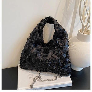 Detail of black sequined evening bag with silver chain strap on a minimalist display