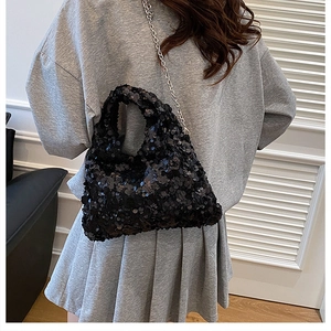 Detail of a sparkling black sequin shoulder bag with a sleek silver metal chain strap