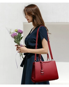 Sac à main élégant en cuir rouge porté avec une robe bleue et des fleurs pour un look chic