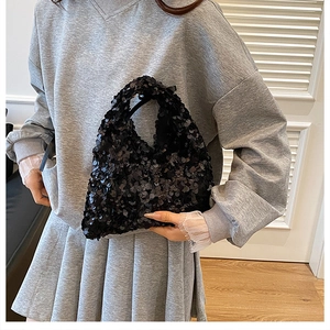 Detail of a black sequin hobo bag showing the reflective texture and compact handle