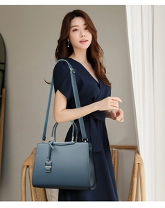 Détail du sac à main bleu Morandi en cuir avec pendentif argenté porté à l'épaule