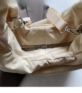 Detail view of smooth silver zipper and soft fabric texture on large cream tote bag