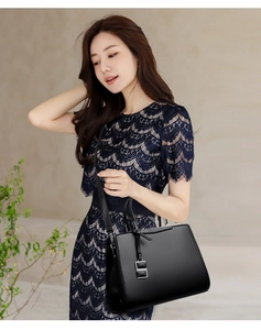 Détail d'un sac à main en cuir grainé noir porté avec une robe élégante en dentelle marine