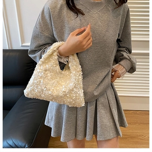 Detail of a white sequined dumpling bag styled with casual grey streetwear outfit