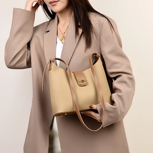 Close-up of beige lychee grain leather handbag with golden lock and brown trim