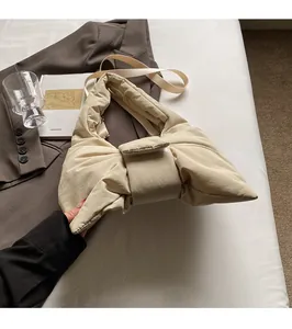 Detail of a beige quilted puffer shoulder bag with a unique knot-shaped design