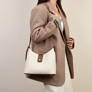 Detail showing the lychee grain texture and metal buckle on the cream shoulder bag