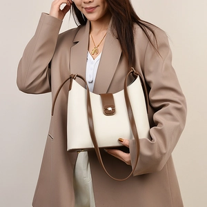 Close-up of cream lychee grain leather bucket bag with gold hardware and brown strap
