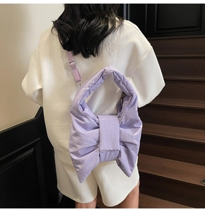 Detail view of the lavender bow-shaped puffy shoulder bag on a female model