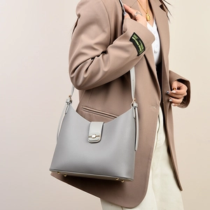 Detail of grey lychee textured leather bucket bag with pale gold hardware on model