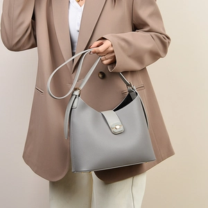 Detail of grey lychee texture leather bucket bag with gold metal buckle and strap