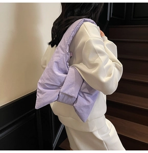 Detail of lavender puffer bag with large bow design on a stylish quilted shoulder bag