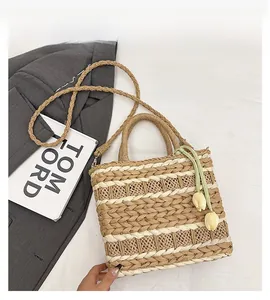 Detailed top view of striped straw tote bag with tulip charm and long shoulder strap