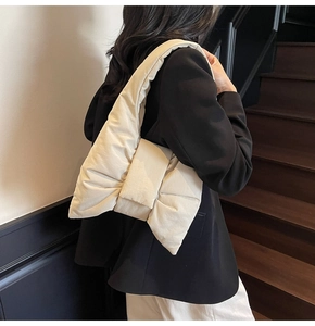 Quilted cream shoulder bag featuring a stylish puff bow design shown on a model