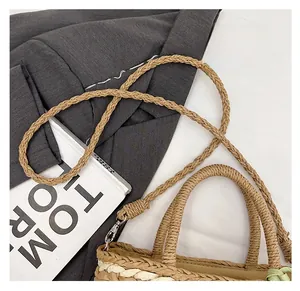 Detail of woven straw handbag handles and detachable shoulder strap with metal buckles