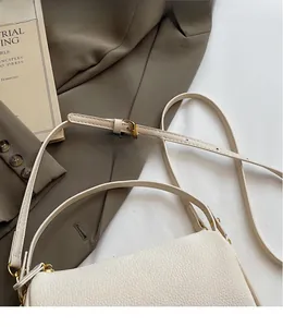 Close-up of cream white lychee texture crossbody bag with adjustable gold hardware