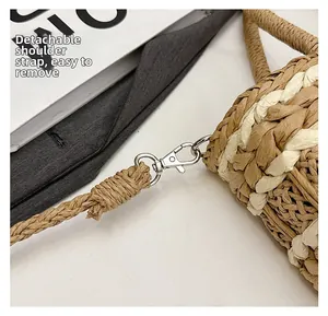 Detail of a straw bag showing the detachable shoulder strap and silver lobster clasp
