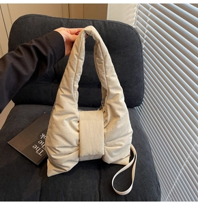 Detail of a beige quilted bow-shaped tote bag showing soft padded fabric texture