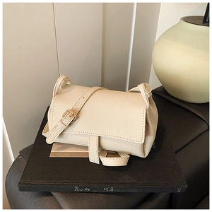 Minimalist beige pebble leather pillow crossbody bag with adjustable gold buckle strap