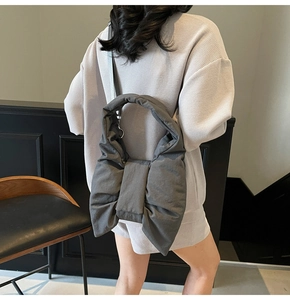 Detail of a dark grey puffer tote bag featuring a large decorative bow and soft texture