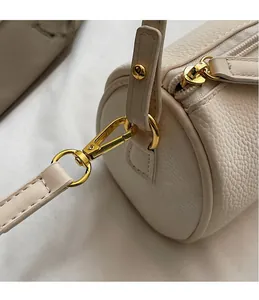 Detail of lychee pattern leather and gold metal hook on beige barrel shoulder bag