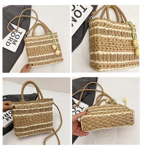 Detail view of straw woven tote with striped patterns and tulip charm on white bedding