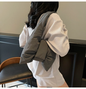 Detail view of large charcoal grey padded bow-shaped shoulder bag in quilted nylon