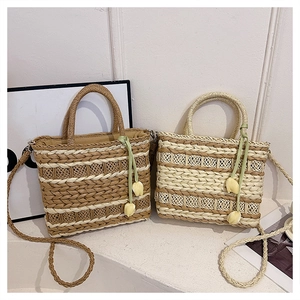 Detailed close-up of woven straw handbag with tulip pendant and green silk ribbon decoration